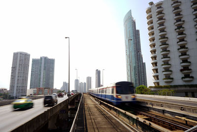 Railroad tracks amidst buildings in city against sky