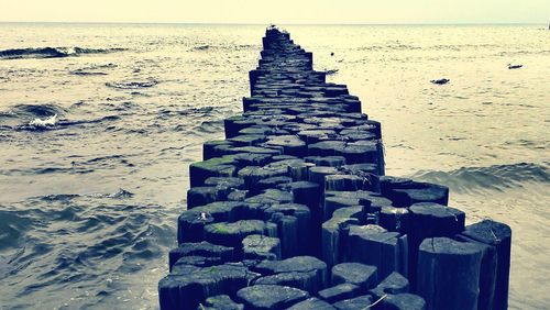 Stone wall on beach against sky