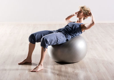 Woman exercising with ball on hardwood floor at gym