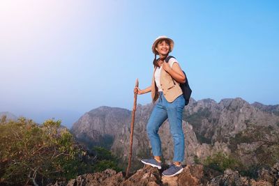 Portrait of man standing on rock against sky