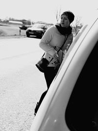 Young woman standing on car against sky