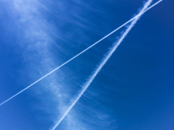 Low angle view of vapor trails against blue sky