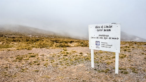 Information sign on field against sky