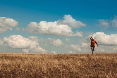 Full length of woman standing on grassy landscape against sky