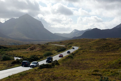 Cars on road by mountains against sky