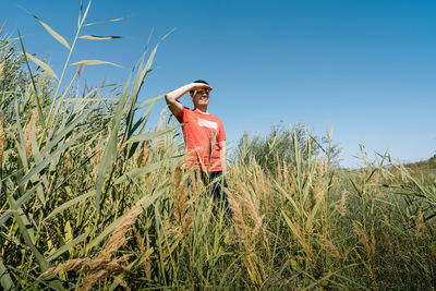 Man standing on reed field against clear sky