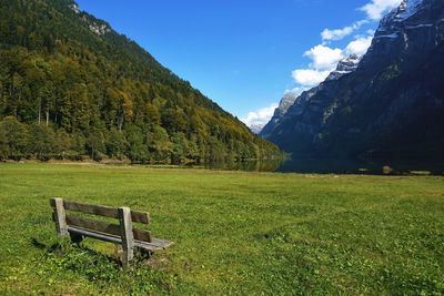 Panoramic view of klontalersee lake with wooden bench in klontal grass valley facing glarus alps