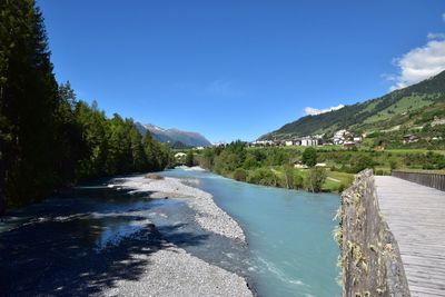 Scenic view of river amidst mountains against blue sky