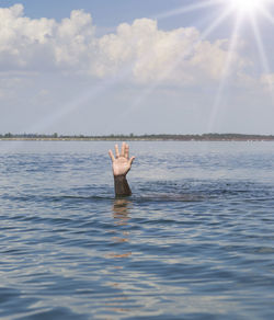 Cropped image of person swimming in sea against sky