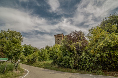 Road by trees against sky