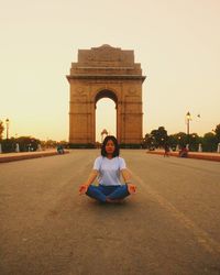 Full length of senior man sitting in city against sky