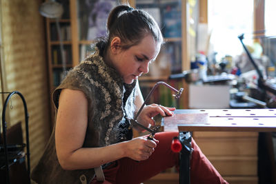 Master in the home workshop saws out a piece of copper metal with a jigsaw, concept creativity