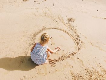 High angle view of girl playing on sand at beach