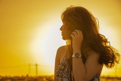 Side view of woman standing against sky during sunset