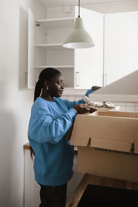 Woman unpacking box in kitchen