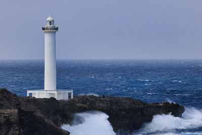 Lighthouse by sea against clear sky