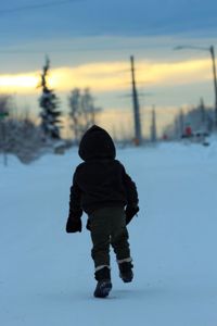 Rear view of girl walking on snow