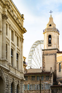 The bell tower of the church of saint ferreol and observation wheel at marseille vieux port, france