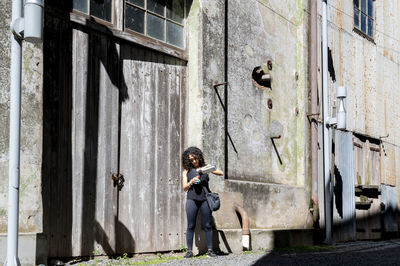 Woman drinking mate while standing outside an abandoned factory.