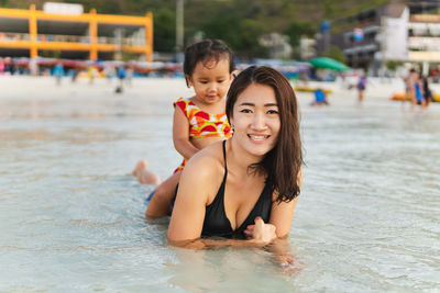 Portrait of mother with daughter lying in sea