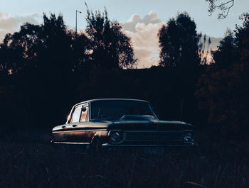 Abandoned car on field against sky