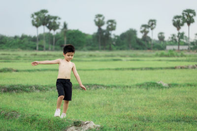 Full length of shirtless boy on field