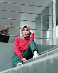 Portrait of a smiling young woman sitting against wall