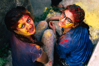 Portrait of smiling friends covered with powder paint sitting outdoors