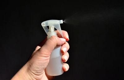 Close-up of person holding hands against black background