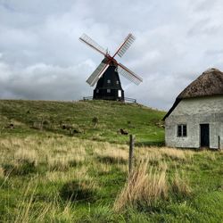 Traditional windmill on land against sky