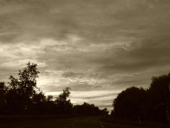 Silhouette trees on landscape against sky at sunset