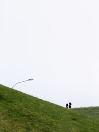 Men walking on field against clear sky