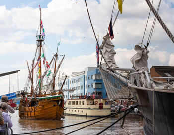 Fishing boats moored at harbor against sky