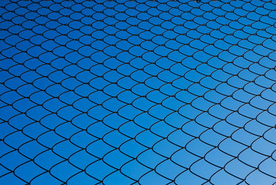 Full frame shot of chainlink fence against blue sky