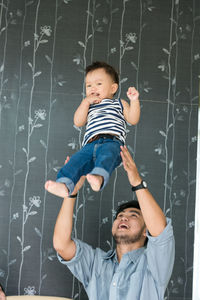 Man carrying baby boy against wall