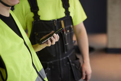 Mid section of worker holding phone