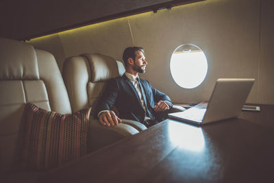 Businessman using laptop in airplane