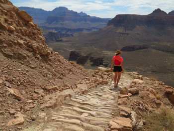 Rear view of woman standing on rocky mountains