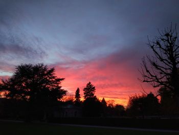 Silhouette trees on landscape against sky at sunset