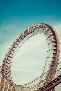 Low angle view of ferris wheel against cloudy sky