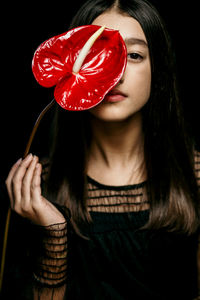 Midsection of woman holding heart shape against black background