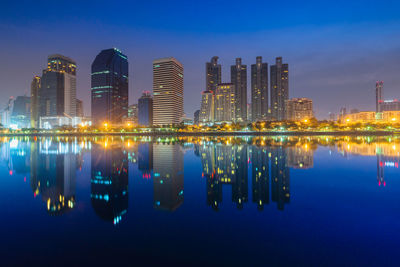 Reflection of illuminated buildings in river against sky