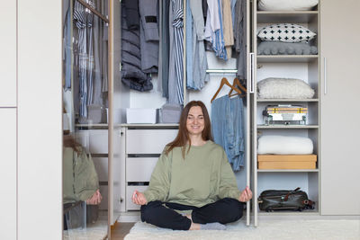 Cheerful woman meditating by closet at home