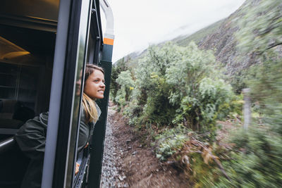 A young woman is looking out of a window on the way to machu picchu