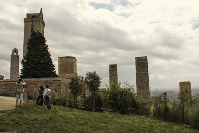 People standing by tower in city against sky