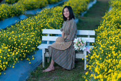 Portrait of a smiling young woman standing on yellow flowering plants