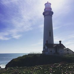 Lighthouse by sea against sky