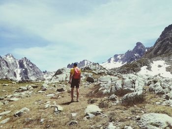 Rear view of man hiking on mountain against sky