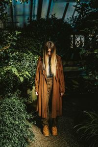 Portrait of young woman standing by plants