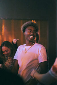 Cheerful young man dancing amidst multiracial friends at nightclub